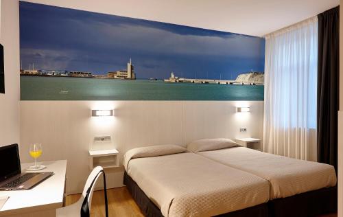 a bedroom with a bed and a desk with a laptop at Hotel Seminario Aeropuerto Bilbao in Derio