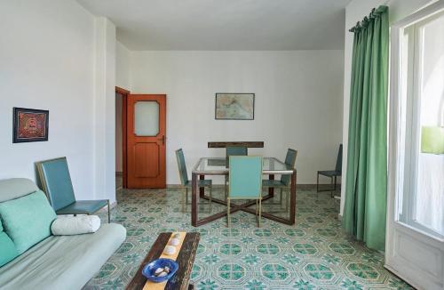 ein Wohnzimmer mit einem Sofa und einem Tisch mit Stühlen in der Unterkunft Il Torrione sul mare G1 in Ischia