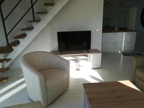 a living room with a white chair and a television at TY KERLUZ - Vue Mer et Plage à 80m in Locquirec