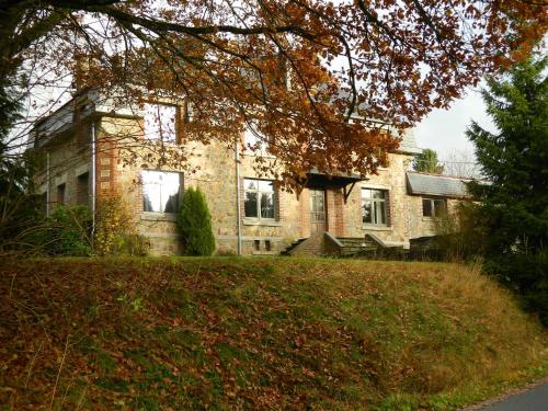 a large brick house on a grassy hill at B&B Les Tchéous in La Gleize