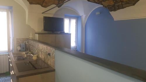 a kitchen with a counter with a sink and a tv at LA CASA BLU DI VEZZARGO in Badalucco