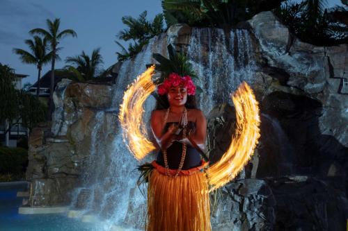 a woman in a fire costume standing in front of a waterfall at Radisson Blu Resort Fiji in Denarau