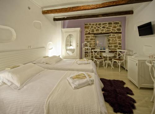a large bedroom with two beds and a dining room at Orologopoulos Mansion Luxury Hotel in Kastoria
