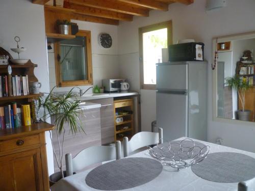 une cuisine avec une table et un réfrigérateur blanc dans l'établissement la petite maison, à Vaugines