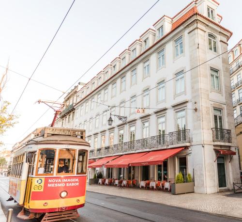 a red and white bus driving down a street at Corpo Santo Lisbon Historical Hotel in Lisbon