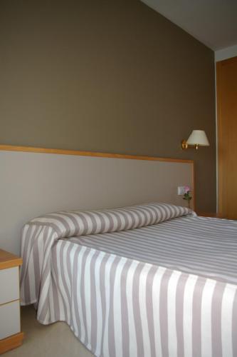 a bedroom with two beds with striped sheets at Hotel Cosmos Tarragona in Tarragona