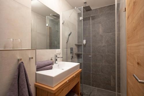 ein Bad mit einem Waschbecken und einer Dusche in der Unterkunft otto steiner appartements pension ellmau & wilder kaiser in Ellmau