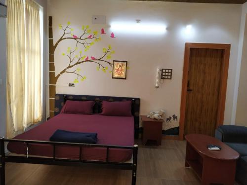 a bedroom with a bed with a tree mural on the wall at Waves Beach House in Puducherry