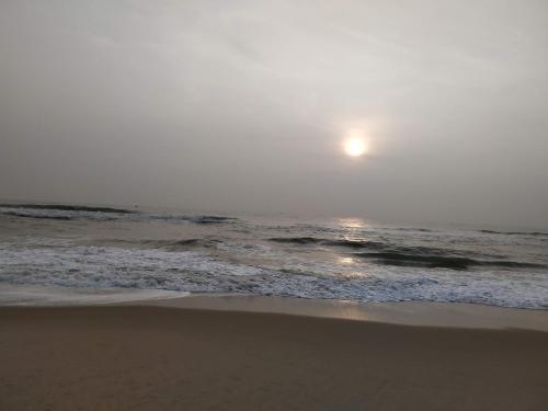 a beach with the sun rising over the ocean at Waves Beach House in Puducherry