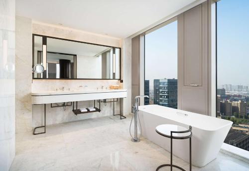 a bathroom with a tub and a sink and a mirror at Radisson Blu Hangzhou Xintiandi in Hangzhou