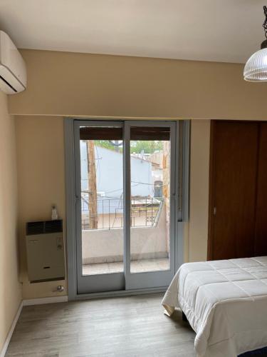 a bedroom with a bed and a sliding glass door at Departamento Ezeiza Centro in Ezeiza