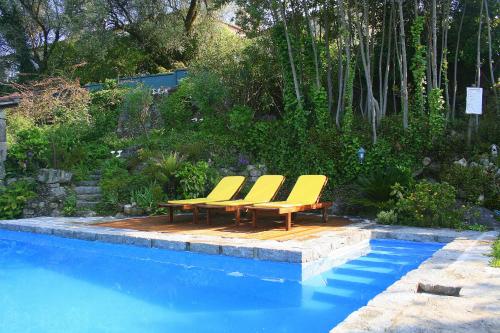 Quatro cadeiras amarelas dispostas em um deck ao lado de uma piscina. em Casa Da Rocha em Caldelas
