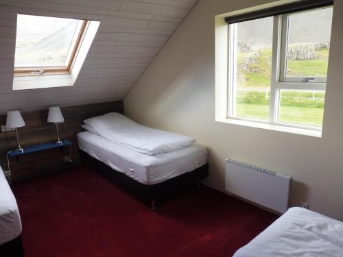 a small room with two beds and two windows at Lón Guesthouse in Thorgeirsstadir