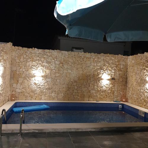a swimming pool with lights on a stone wall at Bella's House 4 com Piscina in Évora