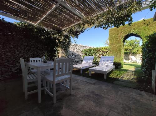 eine Terrasse mit drei Stühlen und einem Tisch und einem Tisch und Bänken in der Unterkunft MASSERIA SALENTINA - Esperienza Autentica in Borgagne