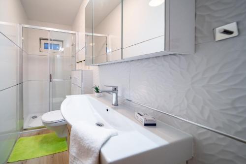 a white bathroom with a sink and a toilet at Apartments Arbis in Lopar
