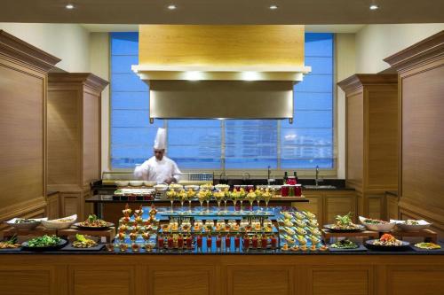 a chef standing behind a counter in a kitchen with food at Kempinski Al Othman Hotel Al Khobar in Al Khobar