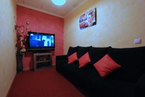 a living room with a black couch and a tv at Hostal Regio in Madrid