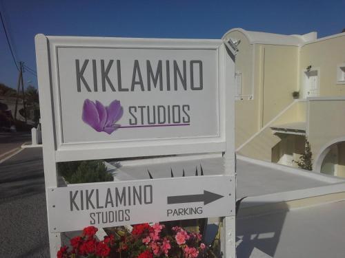 a sign for kalamunda studios with flowers in front of a building at Kiklamino Sunset Studios in Oia
