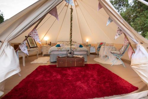 a room with a tent with a red rug at The Primrose at Paradise Valley Glamping in Kerikeri