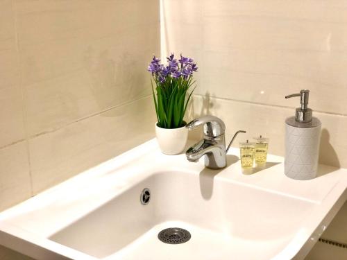a bathroom sink with a vase of purple flowers on it at Apartment in the center in Cherkasy