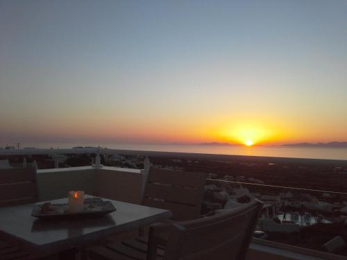a sunset from a balcony with a table and chairs at Kiklamino Sunset Studios in Oia