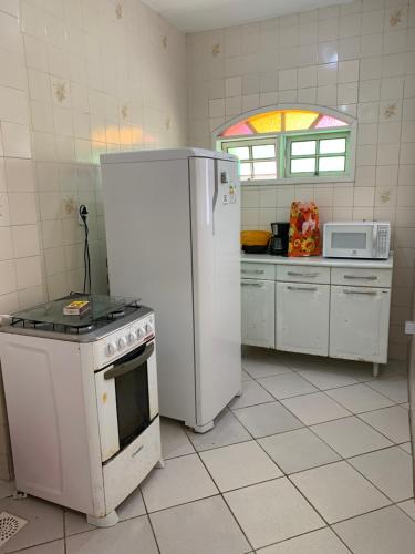 Il comprend une cuisine équipée d'un réfrigérateur blanc et d'une cuisinière. dans l'établissement Casa da Praia das Dunas, à Cabo Frio