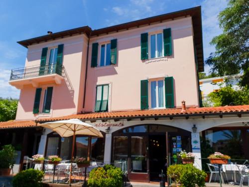 a large pink building with green shutters at Hotel Ristorante Il Caminetto in Diano Marina