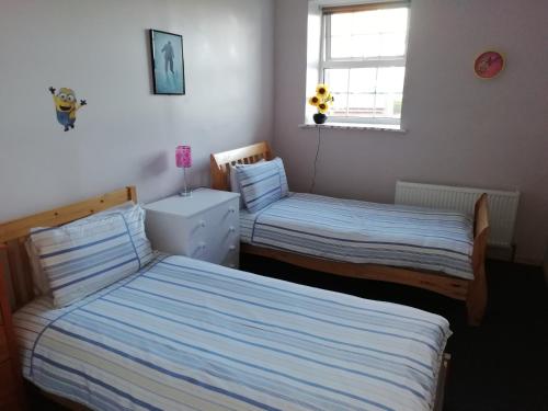 a bedroom with two beds and a window at The River House Self Catering Apartment in Dungloe