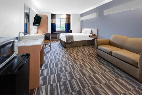 a hotel room with a bed and a couch at Microtel Inn Suite by Wyndham BWI Airport in Linthicum Heights