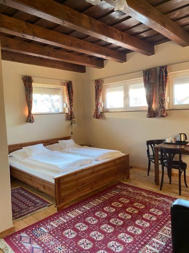 a bedroom with a large bed and a table at Aurora Panzió in Bük