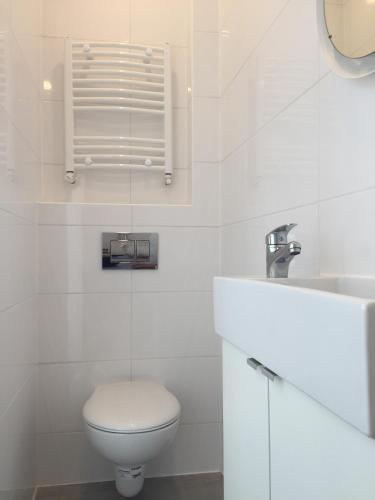 a white bathroom with a toilet and a sink at Apartament Gliwice Centrum Fredry II in Gliwice