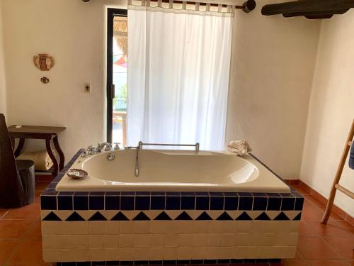 a bath tub in a bathroom with a window at Lo Nuestro Petit Hotel Tulum in Tulum