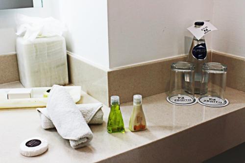 a bathroom counter with a sink with a towel and bottles at Hotel Zenith in Tehuacán