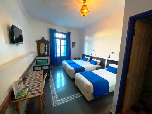 1 dormitorio con 2 camas, mesa y ventana en Hôtel Central, en Casablanca