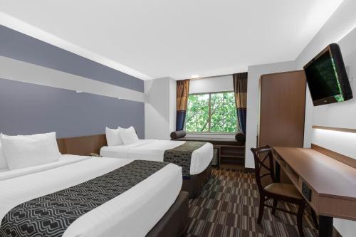 Habitación de hotel con 2 camas y escritorio en Microtel Inn Suite by Wyndham BWI Airport, en Linthicum