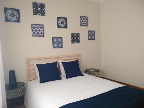 a bedroom with a bed with blue pillows and pictures on the wall at Casas dos Seixos in Moledo