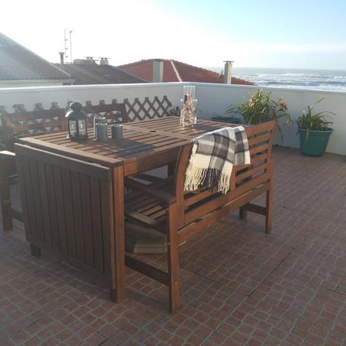 a wooden table and a bench on a patio at Casas dos Seixos in Moledo