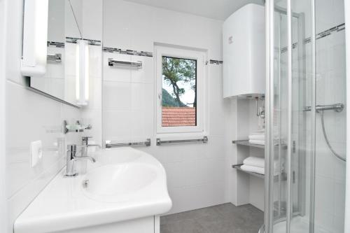 a white bathroom with a sink and a shower at Schützenhof in Sattendorf