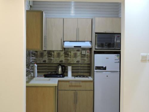a kitchen with wooden cabinets and a white refrigerator at شقق حدائق الزيتون للوحدات السكنية -اقتصادية in Hail