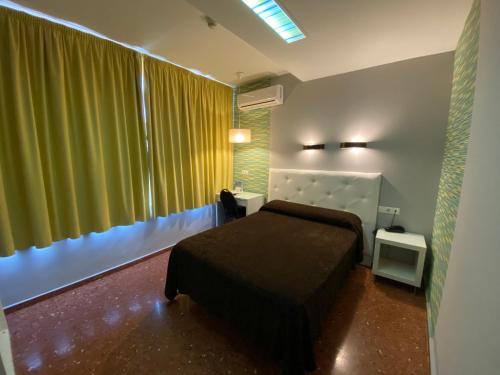 a bedroom with a bed and a green curtain at Hostal Restaurante EstaciÓN in Jaén