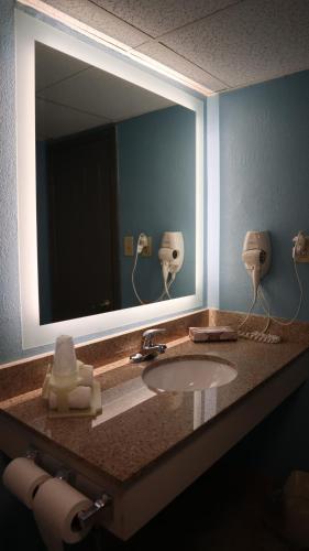 ein Badezimmer mit einem Waschbecken und einem großen Spiegel in der Unterkunft Airport Waterfront Inn in Essington