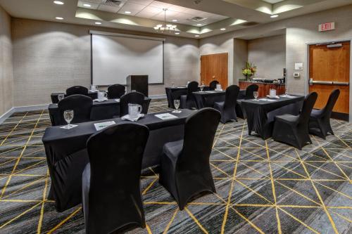 a conference room with tables and chairs and a screen at Holiday Inn Rocky Mount I-95 @ US 64 by IHG in Rocky Mount