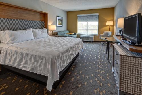 a hotel room with a bed and a flat screen tv at Holiday Inn Rocky Mount I-95 @ US 64 by IHG in Rocky Mount