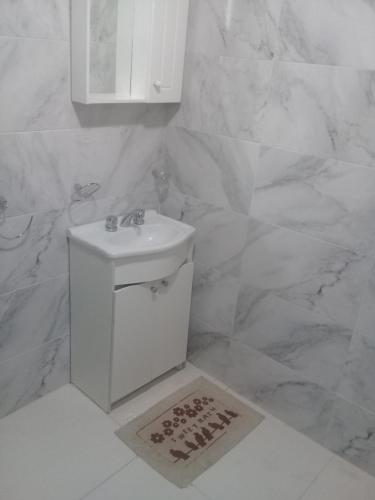 Baño blanco con lavabo y paredes de mármol en Federacion Termal en Federación