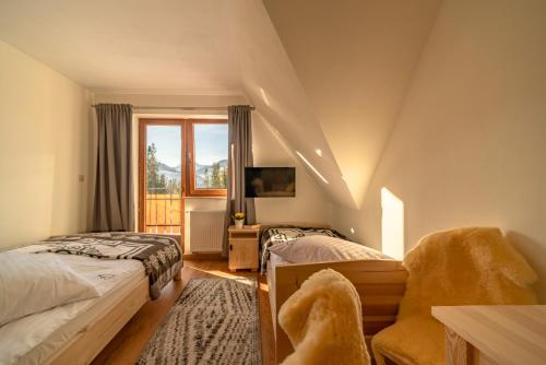 sypialnia z 2 łóżkami, krzesłem i oknem w obiekcie Willa Na Polanie w mieście Kościelisko
