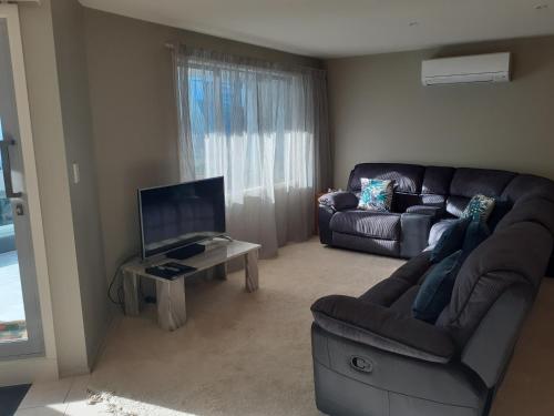 a living room with a couch and a tv at Pavilion Beachfront Apartments in Mount Maunganui