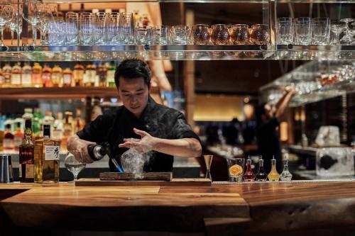 a man standing behind a bar making a drink at Four Seasons Hotel One Dalton Street, Boston in Boston