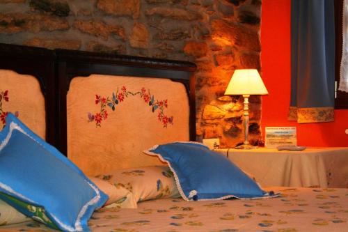 a bed with blue pillows and a table with a lamp at Perlakua Saka in Deba