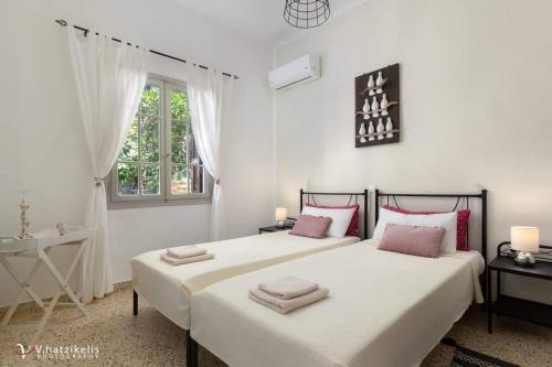 a white bedroom with two beds with towels on them at Aramis Boutique House in Rhodes Town